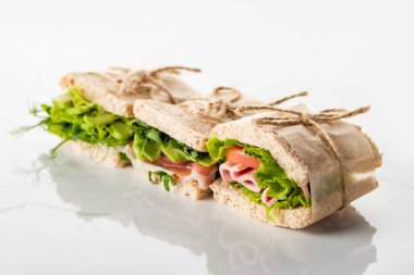 Avokado ve beyaz yüzeyde et bulunan taze yeşil sandviçlerin seçici odağı