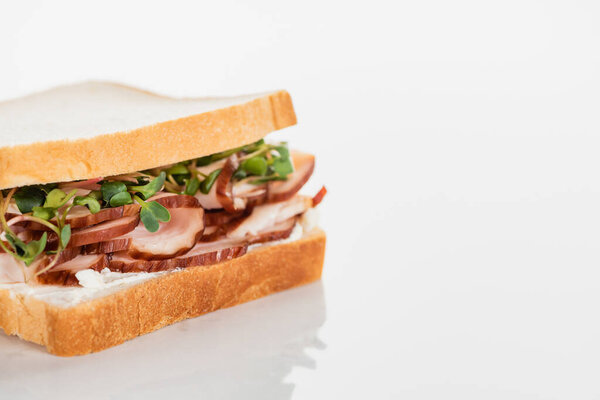 Свежий вкусный сэндвич с мясом и ростками на белой поверхности
