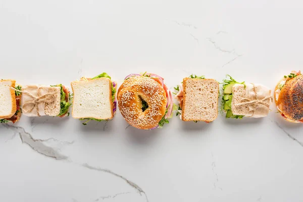 白色大理石表面有新鲜三明治和百吉饼的平铺 — 图库照片
