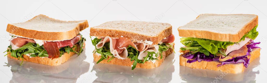 fresh green sandwiches with avocado and jamon on marble white surface, panoramic shot