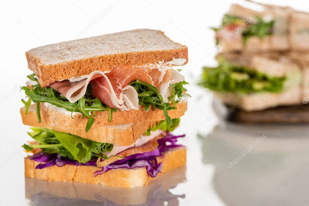 selective focus of fresh sandwiches with arugula and meat on white surface 