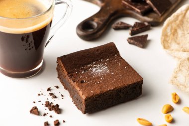  Beyaz arkaplanda kahvenin yanındaki lezzetli browni parçasının seçici odağı