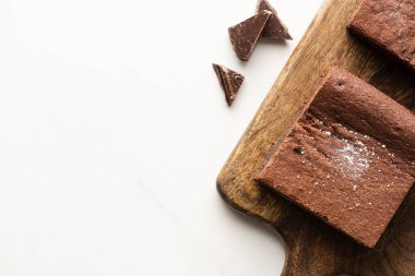 Tahta kesme tahtasındaki lezzetli browni parçalarının beyaz arka planda çikolataları.