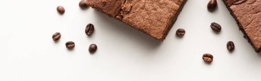 Beyaz arka planda kahve çekirdekleri olan lezzetli browni parçalarının üst görüntüsü, panoramik çekim