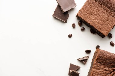 Kahve çekirdekleri ve beyaz arka planda çikolata ile nefis browni parçalarının üst görüntüsü