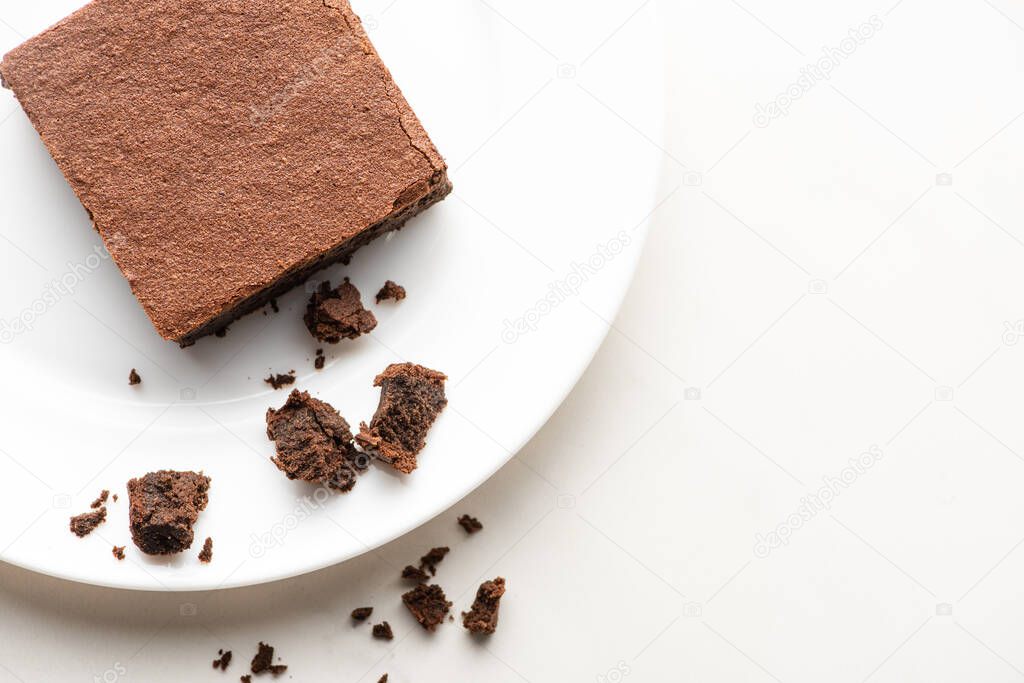 top view of delicious brownie piece on plate on white background