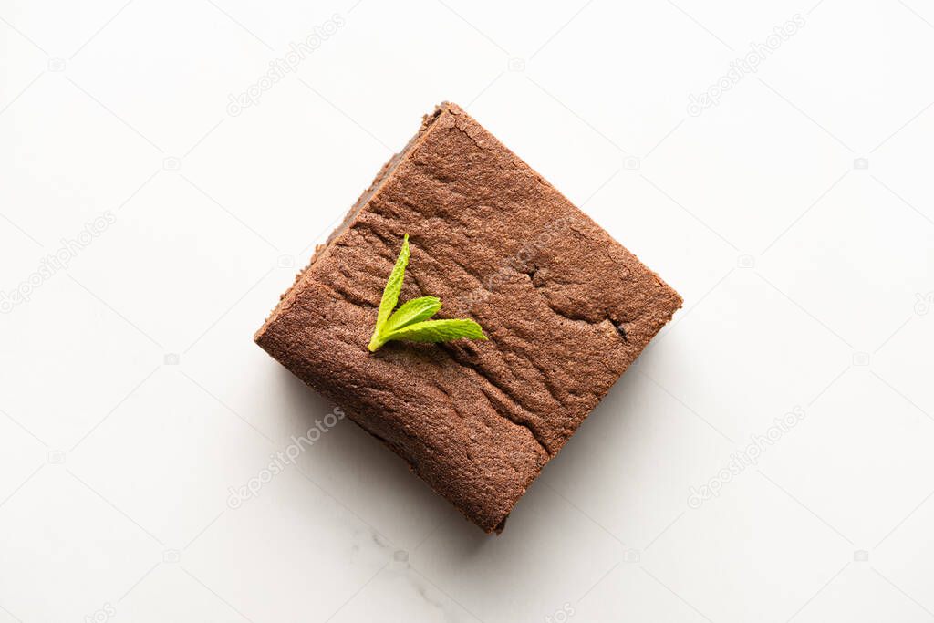 top view of delicious brownie piece with mint on white background