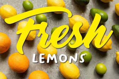 Renkli limonlar, portakallar, avokadolar ve gri beton yüzeyde limonlar, taze limonlar. 