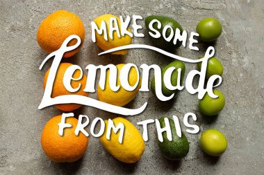 Gri beton yüzeyde renkli portakallarla, avokadoyla, limonlarla ve limonlarla yatar, bu resimden biraz limonata yapar.