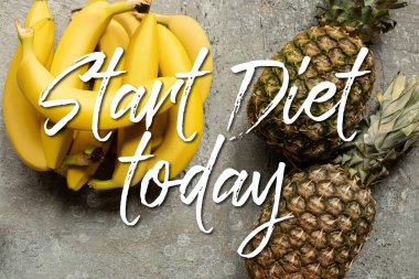 Gri beton yüzeyde renkli lezzetli muz ve ananasların üst görüntüsü, bugün diyete başlayın.