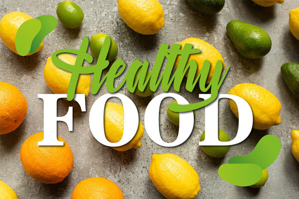 flat lay with colorful limes, oranges, avocado and lemons on grey concrete surface, healthy food illustration
