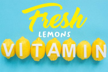 Olgun sarı limonların üst görüntüsü ve mavi arka planda kelime vitamini, taze limon çizimi