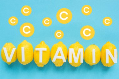 Olgun sarı limonların ve mavi arkaplanda C vitamini illüstrasyonunun üst görüntüsü