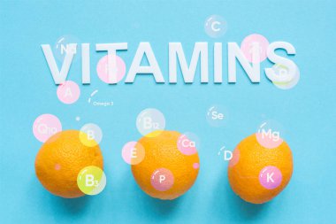 Mavi arkaplanda olgun portakalların ve vitaminlerin üst görünümü
