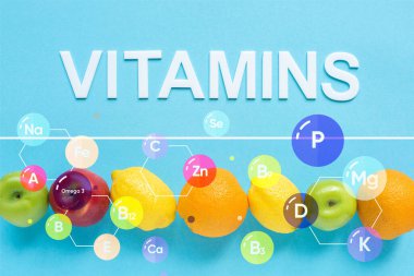 Sıraya dizilmiş olgun meyvelerin üst görünümü ve mavi arkaplanda vitamin illüstrasyonu