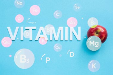 Mavi arkaplanda olgun kırmızı elma ve vitamin resimlerinin üst görünümü