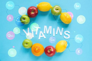 Mavi arkaplanda olgun meyve ve vitamin resimlerinin üst görünümü