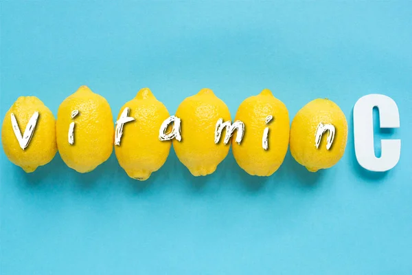 蓝色背景下成熟的黄色柠檬和维生素C插图的顶部视图 — 图库照片