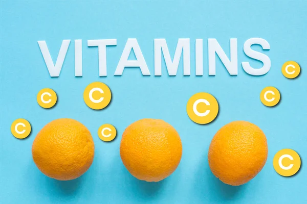 青の背景に熟したオレンジと単語ビタミンのトップビュー — ストック写真