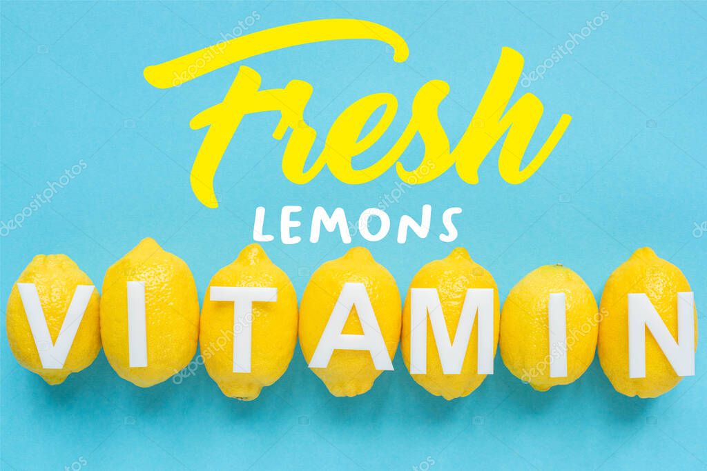 Top view of ripe yellow lemons and word vitamin on blue background, fresh lemons illustration