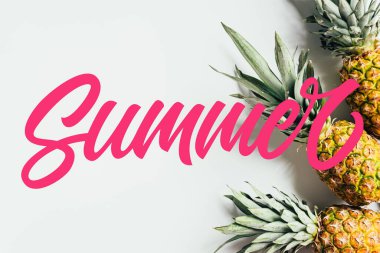 Beyaz arka planda yeşil yapraklı olgun ananasların pembe yaz resimleriyle üst görüntüsü