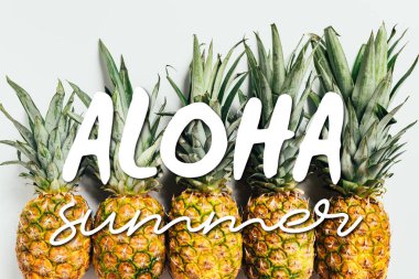 Taze olgun ananaslarla bembeyaz arka planda yeşil yapraklarla bembeyaz uzanmış Aloha yaz resimleriyle