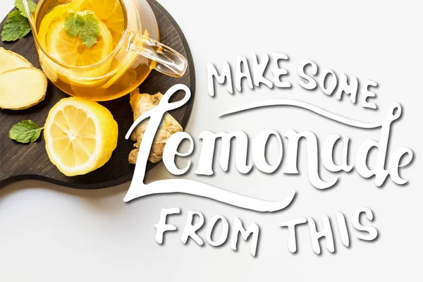 Çaydanlıktaki sıcak çayın beyaz zemin üzerinde zencefil kökü, limon ve nane ile servis edildiği yer. Bu resimden biraz limonata yap.