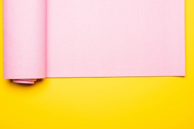 Sarı arkaplanda pembe fitness paspasının üst görünümü