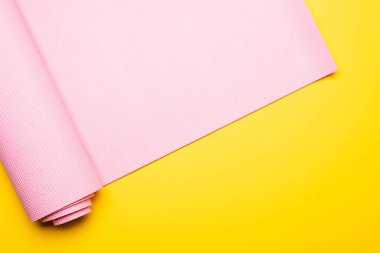 Sarı arkaplanda pembe fitness paspasının üst görünümü