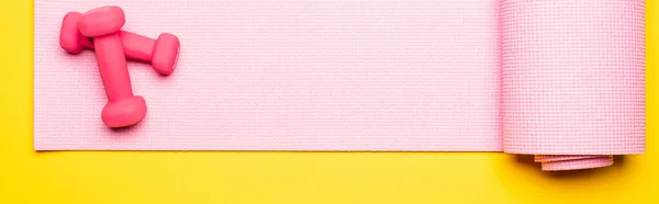 ピンクのフィットネスマットと黄色の背景のダンベルの上からの眺めパノラマ撮影 — ストック写真