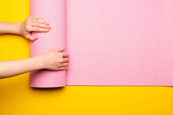 Vista Recortada Mujer Desplegando Alfombra Fitness Rosa Sobre Fondo Amarillo — Foto de Stock