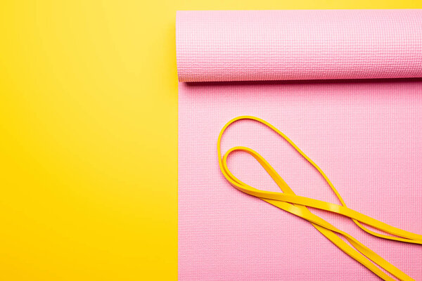top view of elastic band on pink fitness mat on yellow background