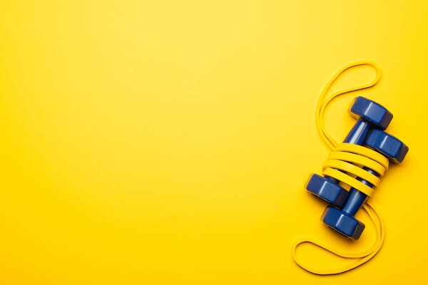 top view of blue dumbbells in resistance band on yellow background