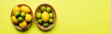 top view of ripe limes and lemons in wicker baskets on colorful background, panoramic crop clipart