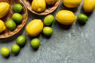 Beton desenli yüzey sepetlerinde olgun sarı limonlar ve yeşil limonlar.