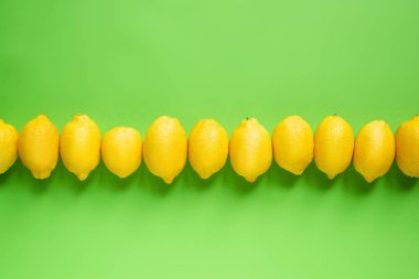top view of ripe yellow lemons in line on green background clipart