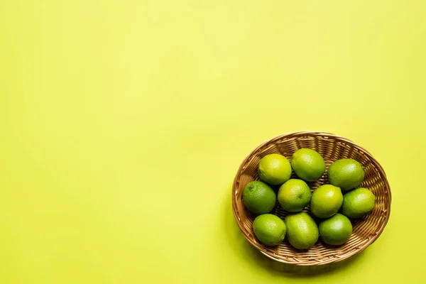 Bovenaanzicht Van Rijpe Limoenen Rieten Mandje Kleurrijke Achtergrond — Stockfoto