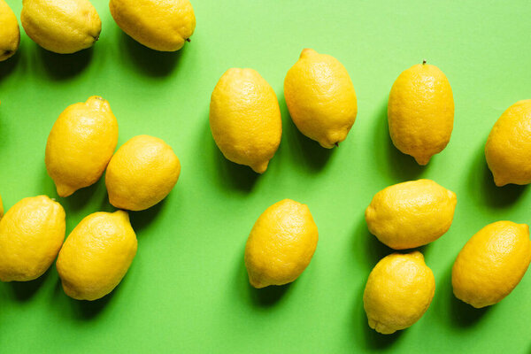 верхний вид спелых желтых лимонов, разбросанных на зеленом фоне