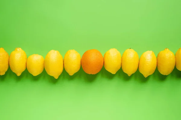 成熟的黄色柠檬和橙色在绿色背景上排成一行的顶部视图 — 图库照片