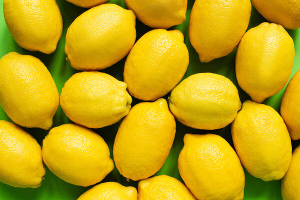 top view of ripe yellow lemons on green background