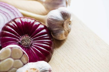 Beyaz üzerine izole edilmiş ahşap kesme tahtasındaki kırmızı soğan ve sarımsak manzarasını kapat.