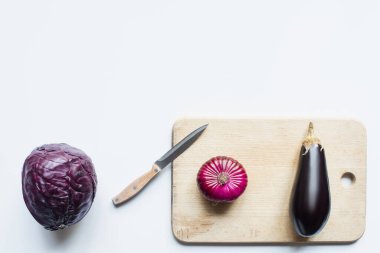 top view of purple whole vegetables, knife and wooden cutting board on white background clipart