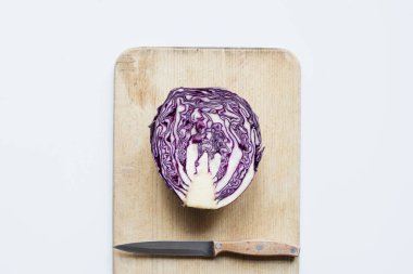 top view of purple cut red cabbage, knife on wooden cutting board isolated on white clipart