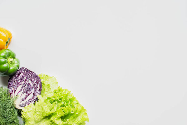 top view of bell peppers, red cabbage, greens on white background