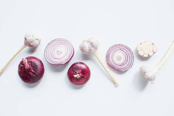 top view of cut and whole red onion and garlic on white background