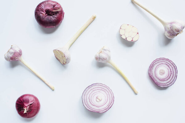 top view of scattered red onion and garlic on white background