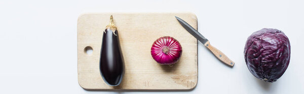 top view of purple whole vegetables, knife and wooden cutting board on white background, panoramic shot