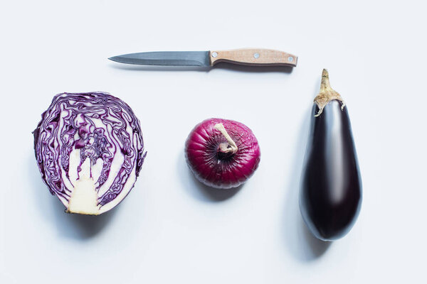 flat lay with knife, red onion, red cabbage, eggplant on white background