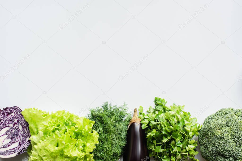 top view of greens, red cabbage and eggplant on white background