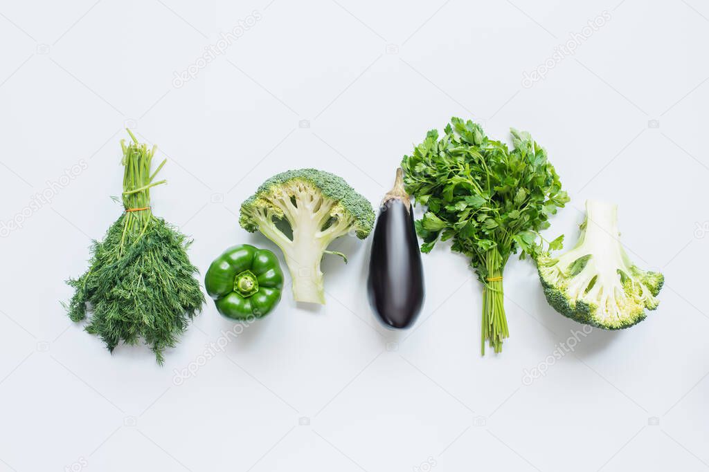 flat lay with assorted green vegetables and eggplant on white background